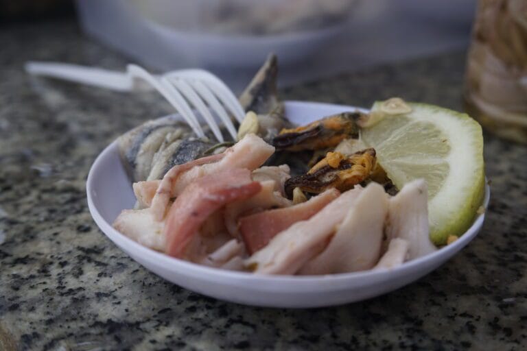 A white bowl filled with a variety of seafood, showcasing an appetizing assortment of fresh ingredients.
