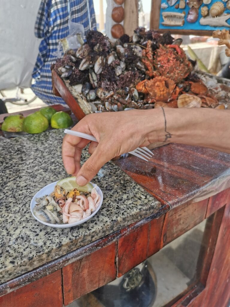 A person prepares to eat Moroccan street food seafood, holding a fork over a colorful plate of fresh ingredients.