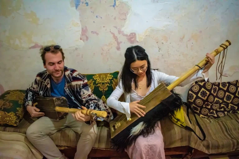 2 tourists playing the traditional gnawa instrument