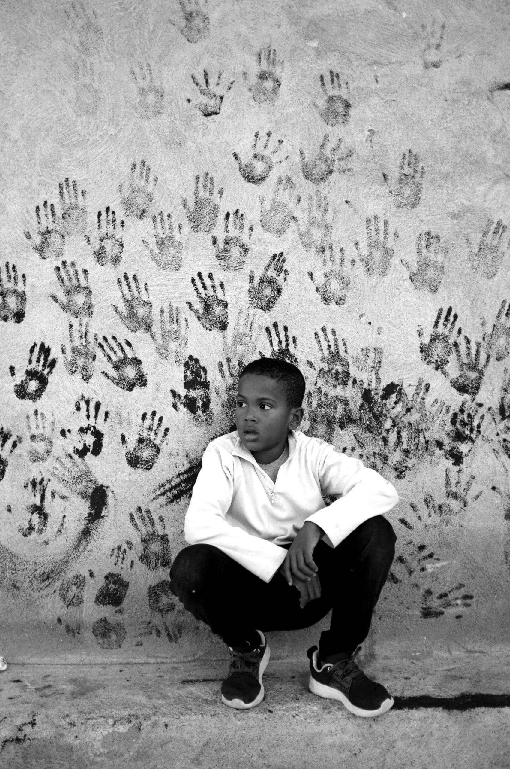 A child sitting near a wall customized with street art in Essaouira