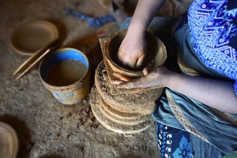 Hands of a craftswoman shaping a clay tagine on a traditional pottery wheel in Oued Laou.