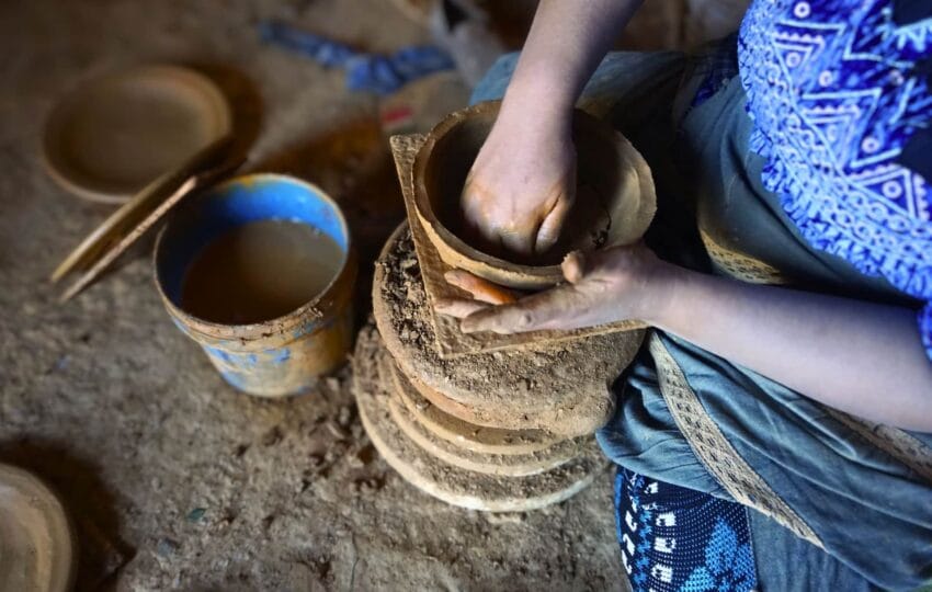 Hands of a craftswoman shaping a clay tagine on a traditional pottery wheel in Oued Laou.