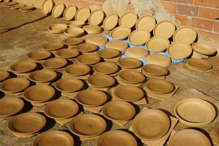 Rows of handmade terracotta tagine bases drying in the Moroccan sun.