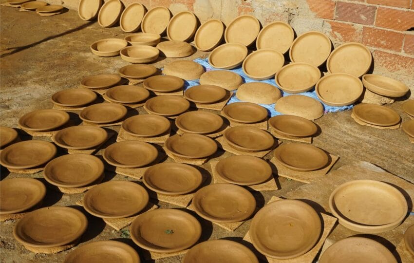 Rows of handmade terracotta tagine bases drying in the Moroccan sun.