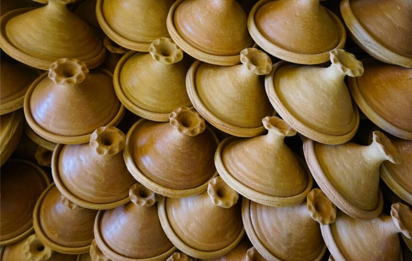 A large stack of handmade, traditional terracotta tagines ready for use.