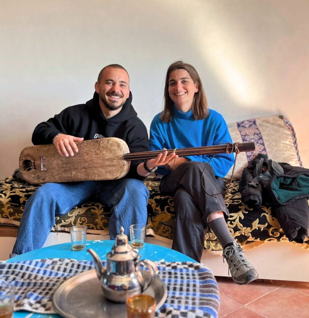 a couple playing guembri and smiling during a gnawa experience in essaouira with morocco unfiltered