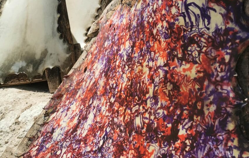 Close-up of a hand-dyed goat skin with red and purple patterns, drying in a traditional tannery in Essaouira.